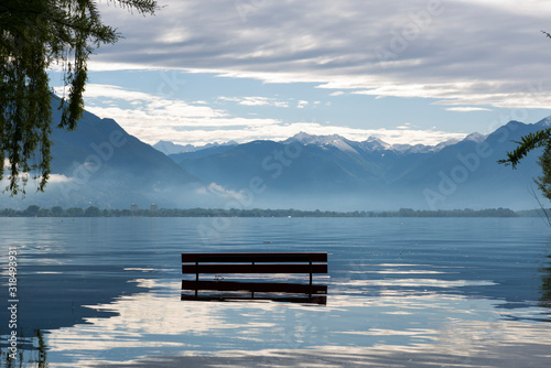 Bench and Tree on a Flooding Alpine Lake with Mountain in Switzerland.
