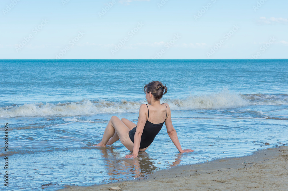Woman Sitting on the Sand Beach with her Swimsuit in Rimini, Italy. Woman Sitting on the Sand Beach with her Swimsuit in Rimini, Italy.