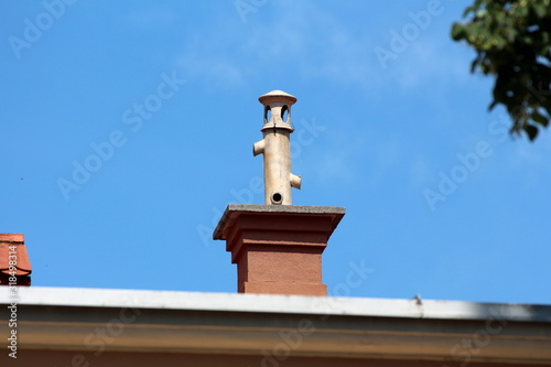 Fotografie Chimney with unusual pipe on top with multiple openings and protective cap on to