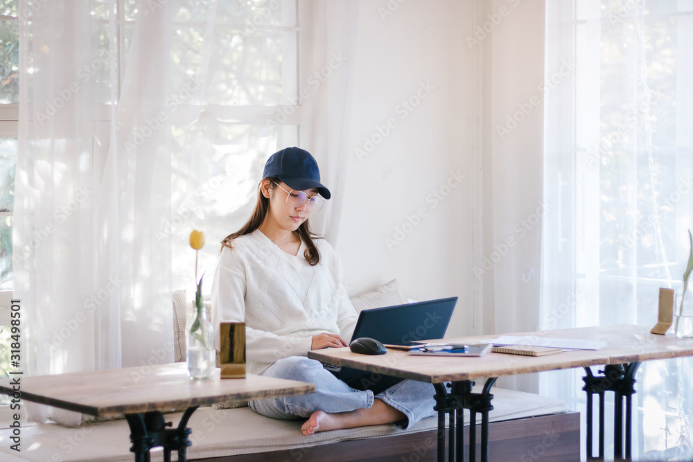Young female wearing hat and glasses working with laptop in cafe Young female wearing hat and glasses working with laptop in cafe