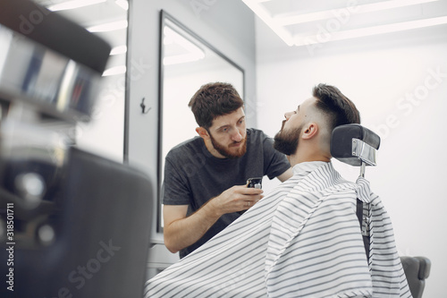 Man with a beard. Hairdresser with a client. Brunette in a barbershop