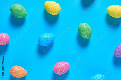 Many scattered colorful eggs with glitters lies on blue table on kitchen. Easter concept. Top view. Close-up © OlekStock