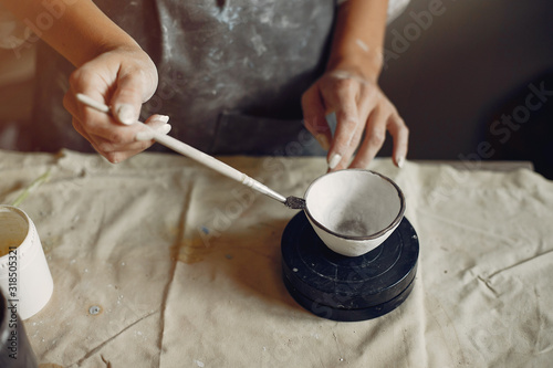 Woman in a pottery. Master make a dishes. Artist works with a clay