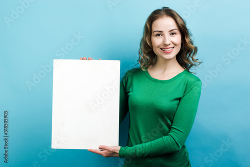 Young beautiful woman holding white object on her hand on blue background