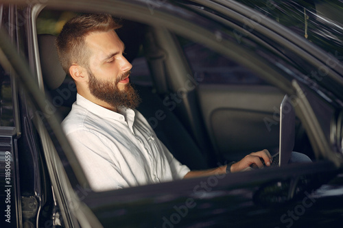 Handsome man in a white shirt. Businessman working in a car. Man use the laptop © prostooleh