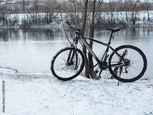 Bicycle in the winter snow Park by the river © pavelkant