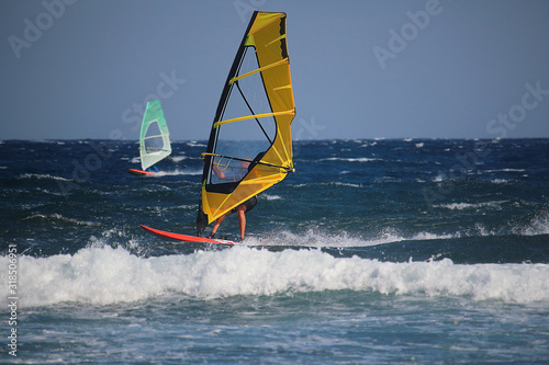 Windsurfer with yellow sail in turquoise water of the Atlantic Ocean