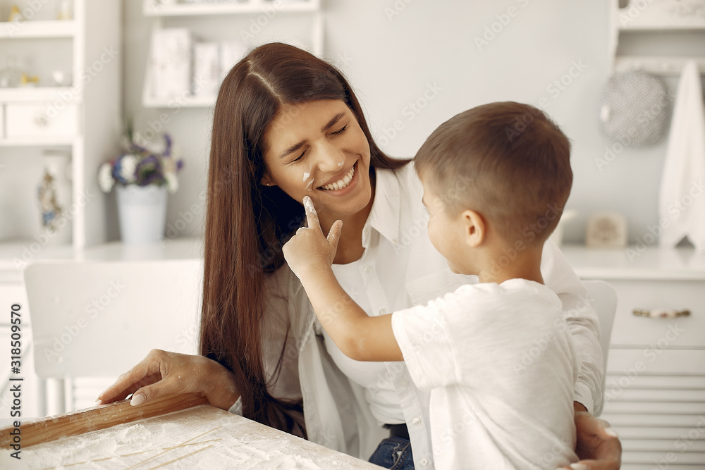 Fototapeta premium Family in a kitchen. Beautiful mother with little son. Flour at the table