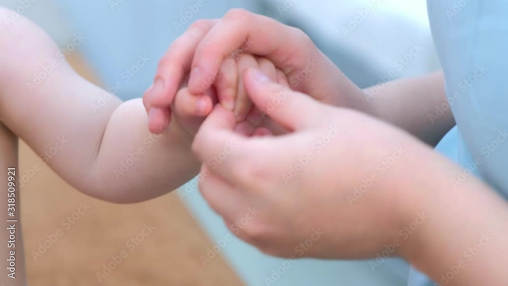 Professional doctor masseur is making massage to baby on hand, palm and fingers in clinic, hands closeup. Therapist's hands gently massaging baby's hand. Medicine cure for children. Babycare concept. Professional doctor masseur is making massage to baby on hand, palm and fingers in clinic, hands closeup. Therapist's hands gently massaging baby's hand. Medicine cure for children. Babycare concept.