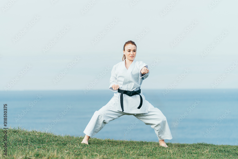 Young female redhead karate fighter hitting a left punch