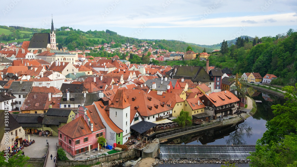 Aerial panoramic view of the typical colorful houses of Cesky Krumlov with Vltava river at the foreground and St. Vitus Church at the background (Czech Republic)