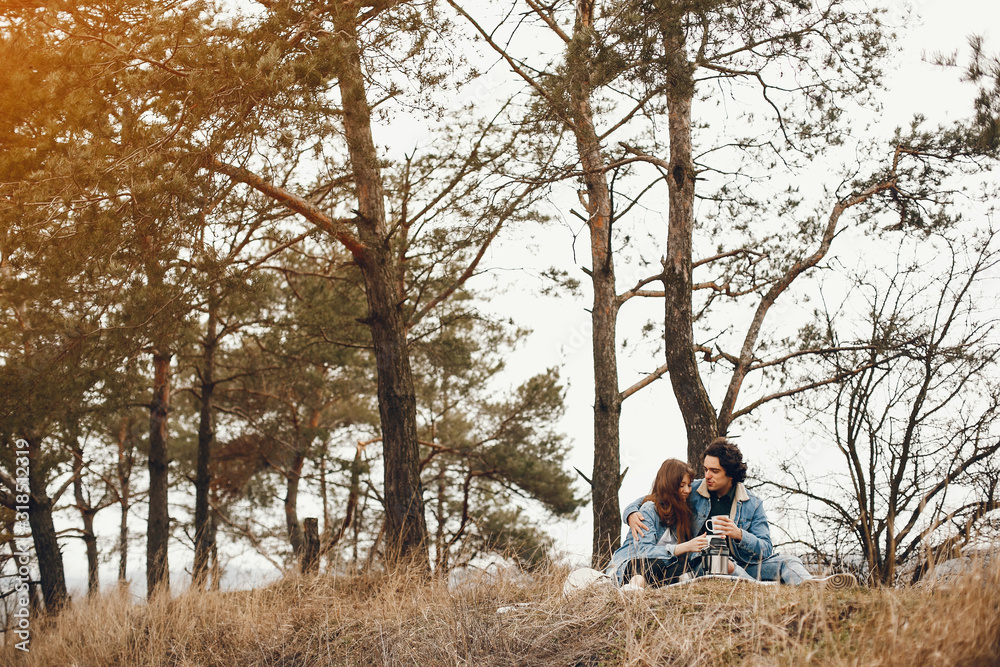 gentle and stylish couple sitting in the autumn park and drinking a tea gentle and stylish couple sitting in the autumn park and drinking a tea