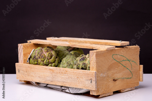 Small wooden crate from the local market with a lot of Sugar-apples or 'Fruta de Conde' [Earl Fruit] as it is known in Brazil against a dark background photo