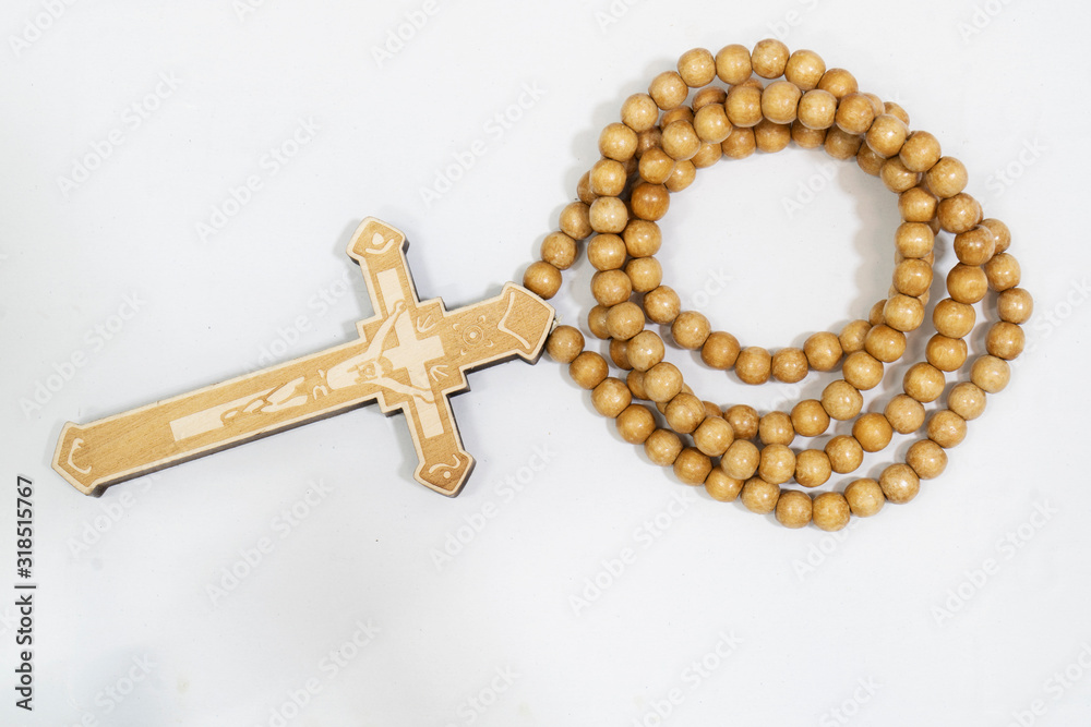 rosary beads with cross made of gray wood on a white background, selected focus on christ, narrow depth of field. rosary beads with cross made of gray wood on a white background, selected focus on christ, narrow depth of field.