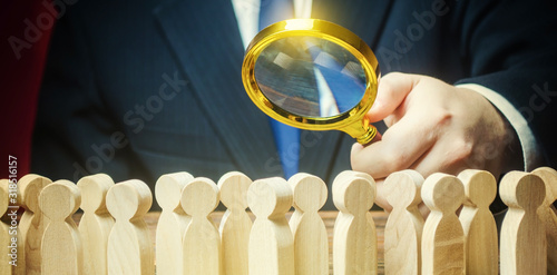 Businessman is studying a crowd of people with a magnifying glass. Hr search candidates for work, staff recruiting. Society, demographic. Market and customers research. Citizens electorate. Sociology photo