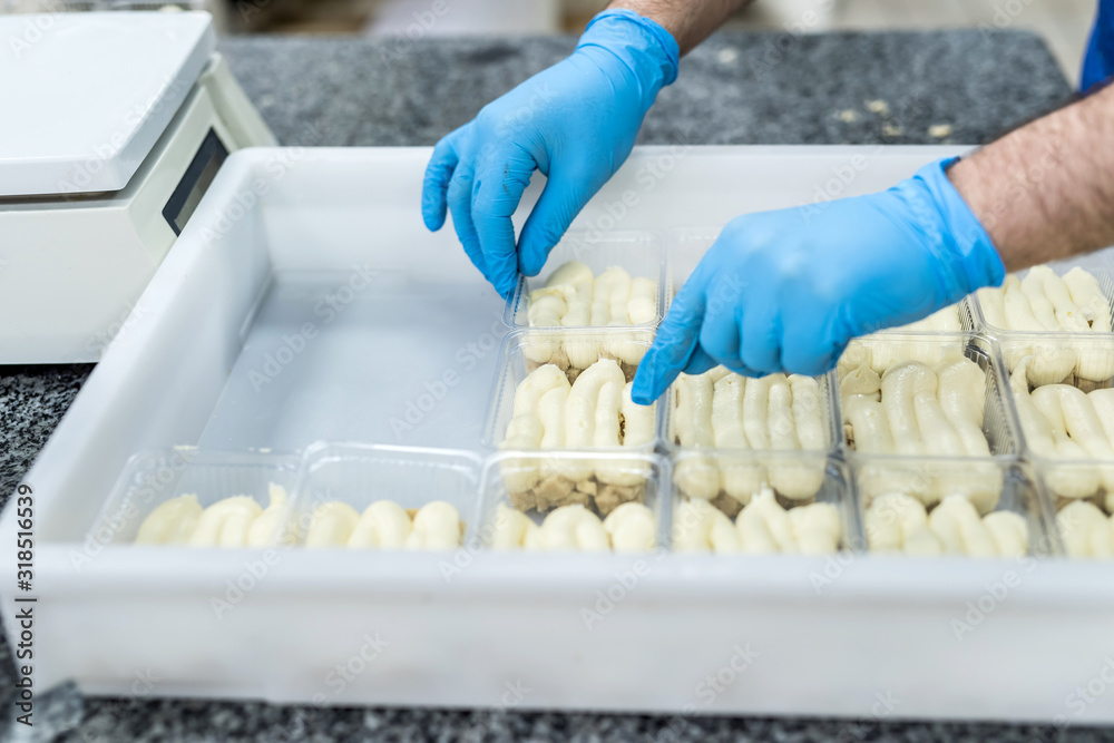 Confector's hands with desserts in plastic package putting it for freezing. Industrial manufacturing of food Confector's hands with desserts in plastic package putting it for freezing. Industrial manufacturing of food