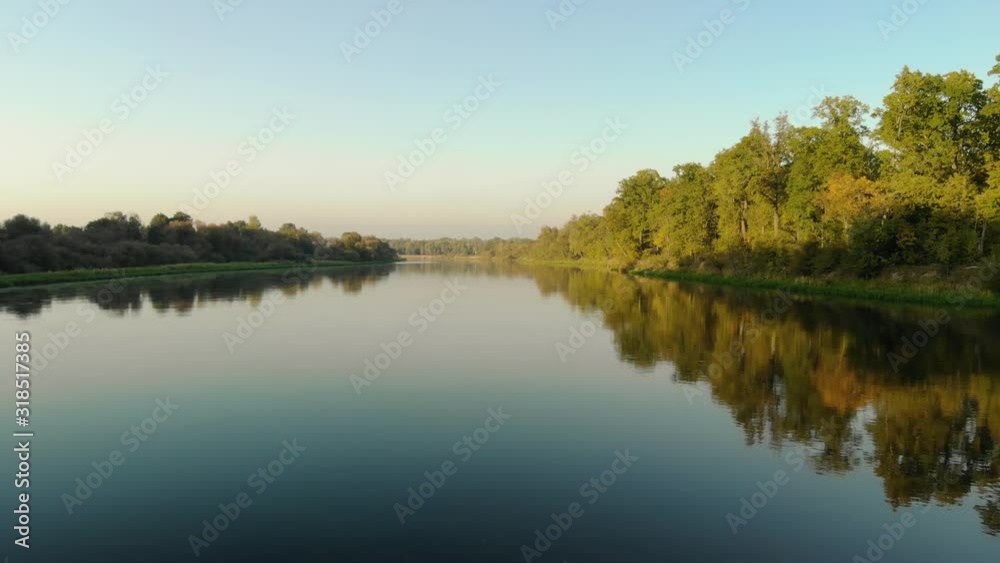 The rainforest is perfectly reflected in a small river with a slow current, and the sun shines on the tops of the trees. Landscape with beautiful blue sky The rainforest is perfectly reflected in a small river with a slow current, and the sun shines on the tops of the trees. Landscape with beautiful blue sky