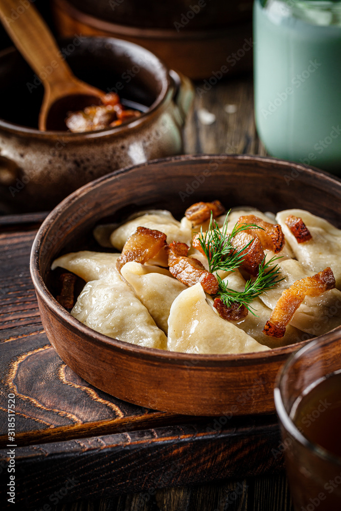 Ukrainian cuisine. vareniki with potatoes and fried pork fat - cracklings. Serving dishes in a Ukrainian style restaurant with sour cream on a wooden background. background image, copy space text Ukrainian cuisine. vareniki with potatoes and fried pork fat - cracklings. Serving dishes in a Ukrainian style restaurant with sour cream on a wooden background. background image, copy space text