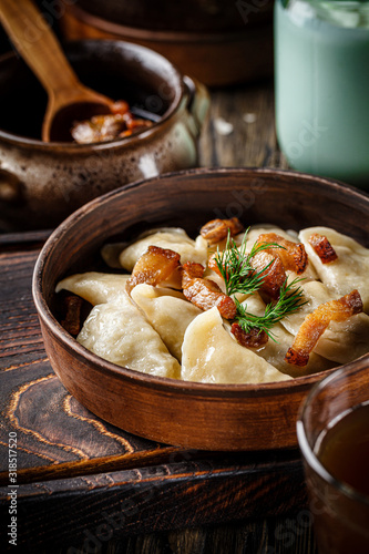 Ukrainian cuisine. vareniki with potatoes and fried pork fat - cracklings. Serving dishes in a Ukrainian style restaurant with sour cream on a wooden background. background image, copy space text