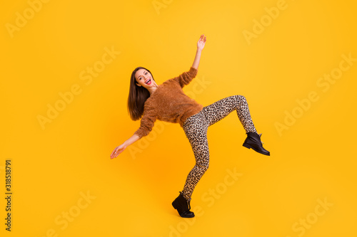 Full length profile photo of crazy lady raising leg high trend look robot dance falling down spread hands wear fur sweater leopard trousers shoes isolated yellow color background