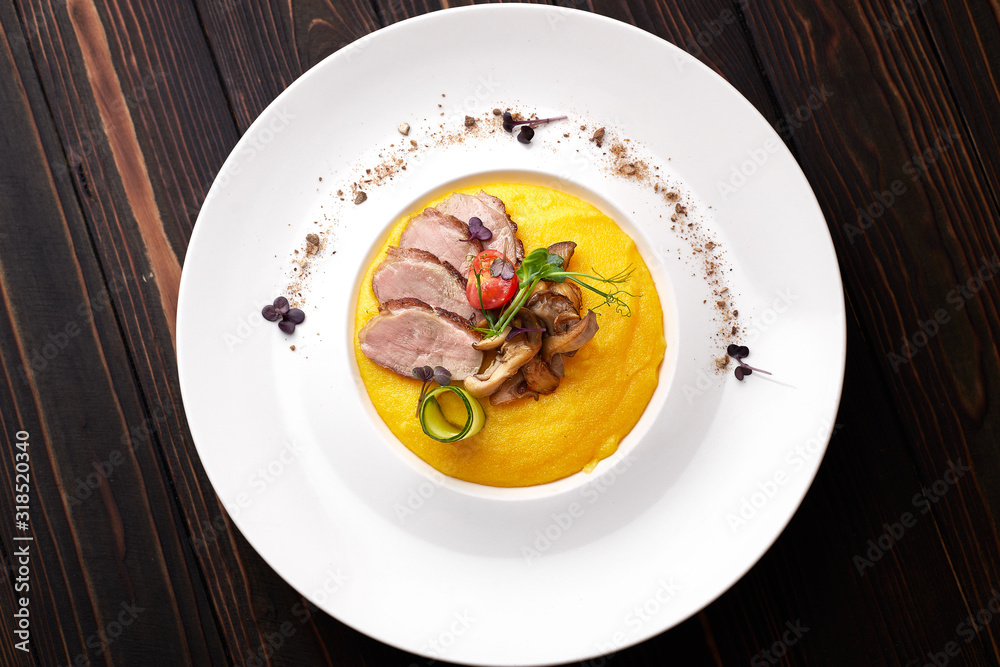 Corn porridge with meat and mushrooms, on a white plate. polenta, ugali, Banosh, mamaliga Corn porridge with meat and mushrooms, on a white plate. polenta, ugali, Banosh, mamaliga