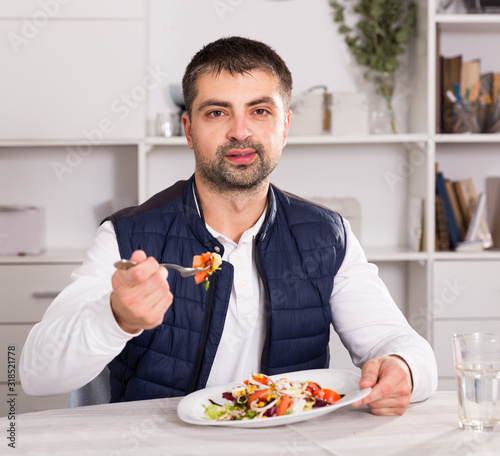 Young man eating vegetable salad from plato