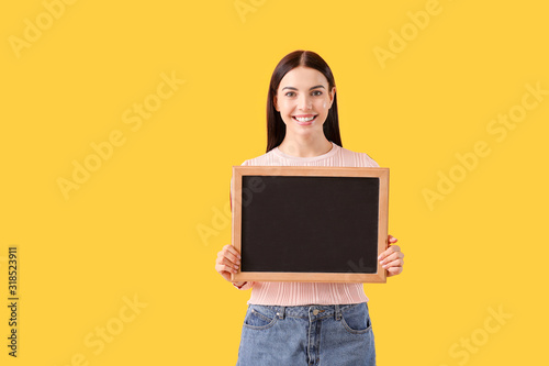 Young woman with chalkboard on color background