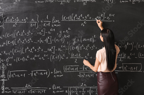 Female teacher writing on b...