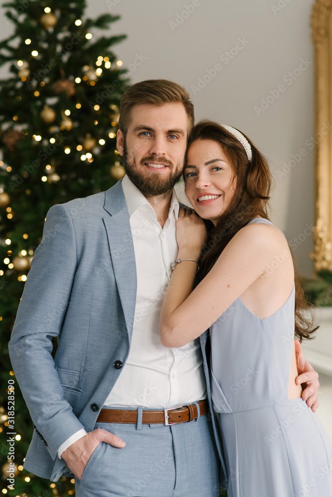 Attractive and loving man and girl on the background of the Christmas tree at home, the concept of Christmas love story