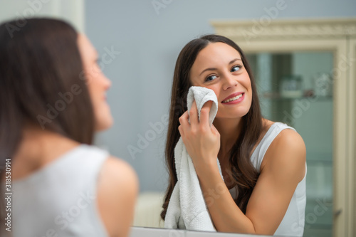 Portrait of young happy woman who is washing her face.