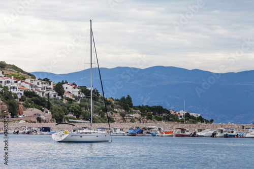 View of the sea, mountains and ship in cloudy weather. Coast with houses on background