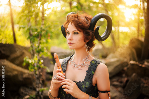 Foto A girl in the image of a faun stands with a wooden flute