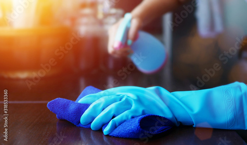 hand in blue rubber glove holding blue microfiber cleaning cloth and spray bottle with sterilizing solution make cleaning and disinfection for good hygiene photo