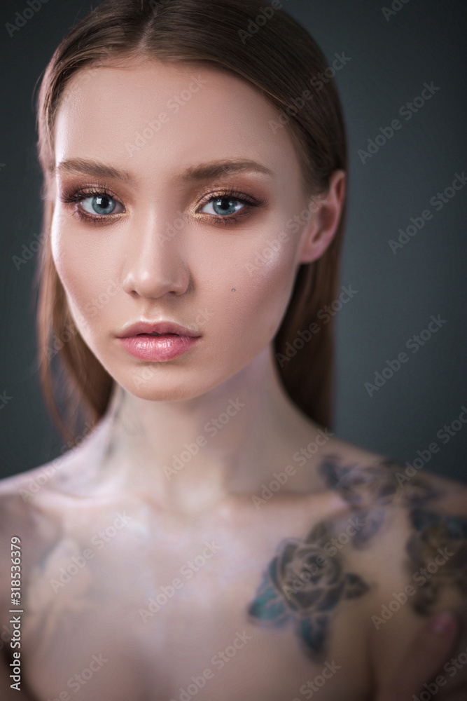 Studio portrait of a model. Body art gray roses. Beautiful girl on gray background Studio portrait of a model. Body art gray roses. Beautiful girl on gray background