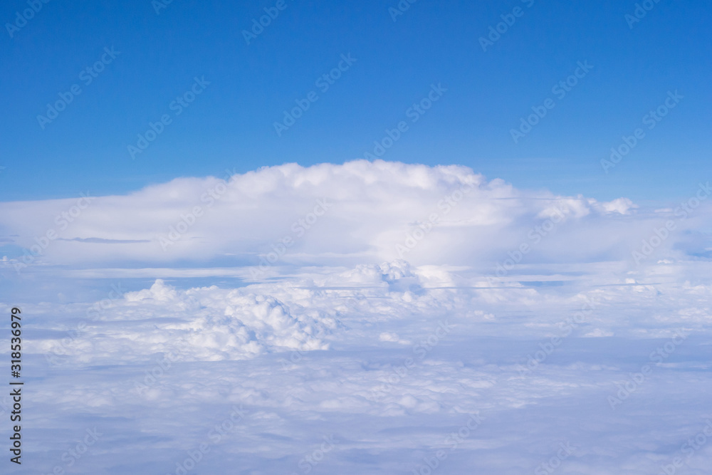 Beautiful view from airplane window above the clouds. Bright blue sky and white clouds. Skyline background with copy space.