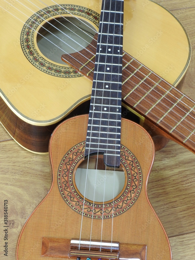 Close-up of an acoustic guitar and a Brazilian string musical instrument: cavaquinho, on a wooden surface. They are widely used to accompany samba and choro, two popular Brazilian rhythms. Top view.