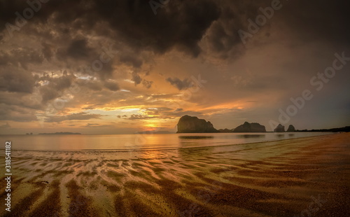 view seaside panorama evening of mountains on the beach with reflection on woater and yellow sun light with cloudy sky background  sunset with raining at Pak Meng Beach  Trang Province  Thailand.