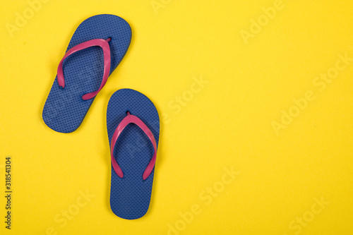 Pink and blue flip flops on a yellow background with copy space photo