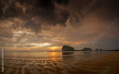 view seaside panorama evening of mountains on the beach with reflection on woater and yellow sun light with cloudy sky background  sunset with raining at Pak Meng Beach  Trang Province  Thailand.