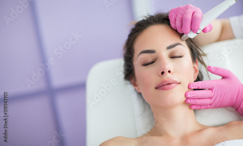 Beautiful young woman getting rejuvenating and tightening skin treatment at professional cosmetic salon.