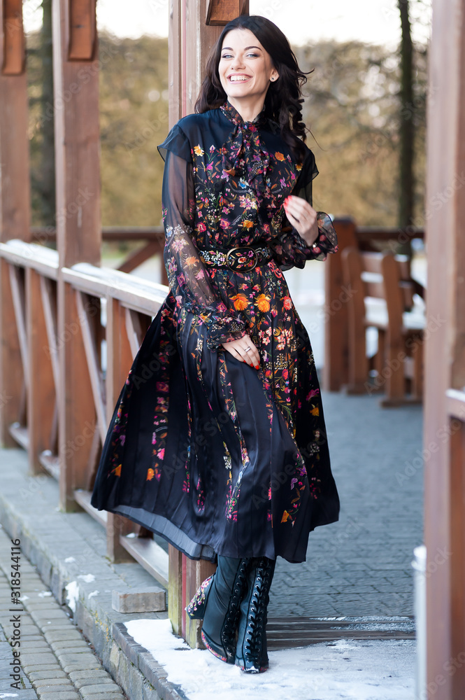 Beautiful woman with smile in dress near wooden handrail