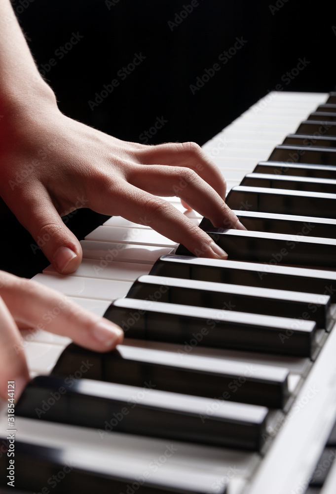 Obraz premium Closeup view of the child hands playing on electronic synthesizer piano keys. Vertical photo ready for music shops, posters, advertising booklets, business cards, web presentations. Place for text