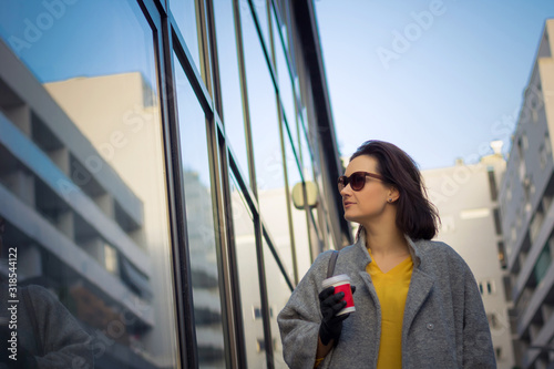 Woman with takeaway coffee walking in the city.