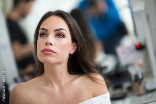 Makeup artist preparing beautiful female model for shooting