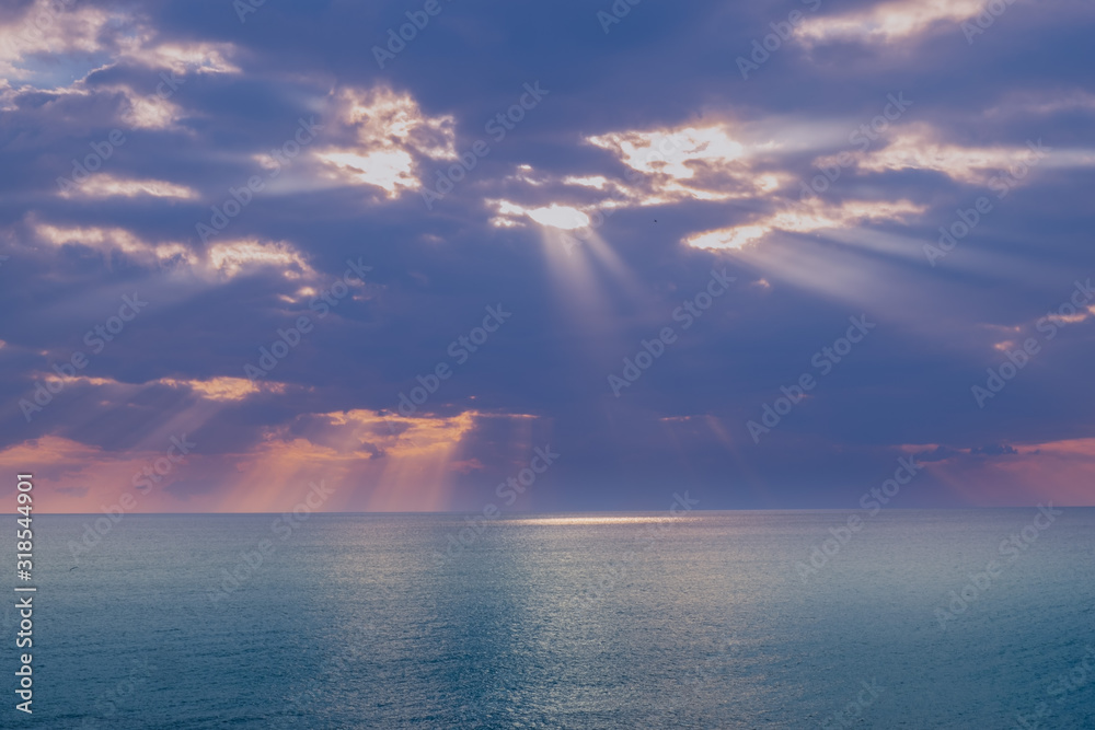 Raggi di luce si specchiano sul mare attraverso un cielo nuvoloso