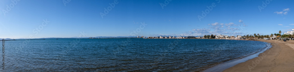 Seascape in Roses, Catalonia, Spain. City on the coast on blue sky and mountain background. Beautiful sandy beach panoramic view in the sunny day, natural background. Bay in the Mediterranean.