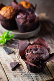 Dark chocolate muffin with mint on a wooden table, homemade baking
