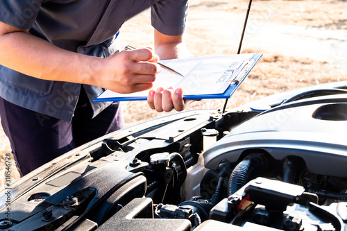 The hand of the mechanic is checking the order of the engine and note the information