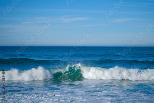 Large ocean waves on a clear sunny day on the European coast. Winter holidays on the Atlantic ocean. High waves, surfing in Europe. Tidal bore. Bay of Biscay, Spain.