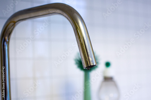 Kitchen faucet on the background of a white tiled wall.